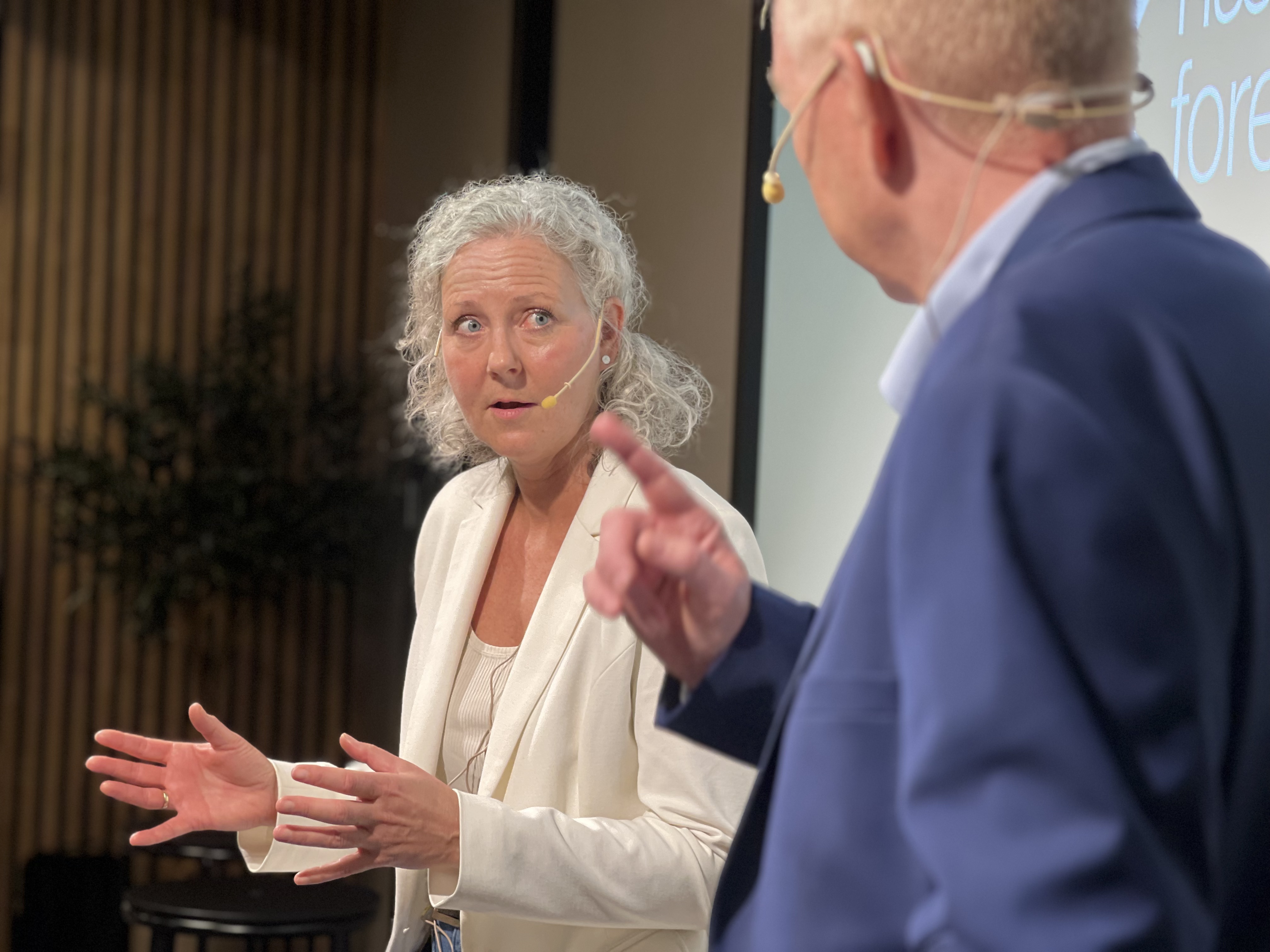 Jill Akselsen på scene gestikulerer iført hvit bluse